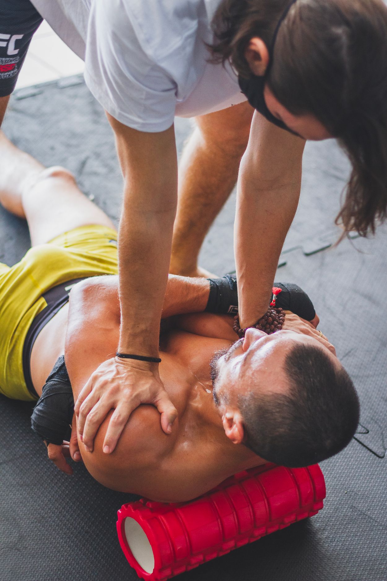 Trainer helping an athlete stretch on a foam roller (editorial stock photography)